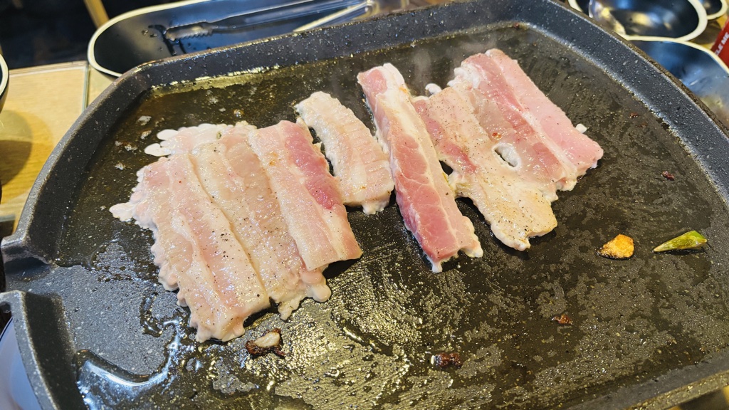鉄板の上で焼かれるサムギョプサルの生肉