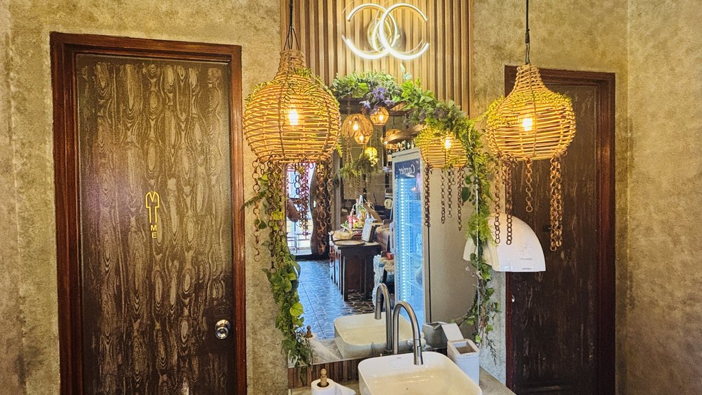 ラタンのランプと植物で飾られた、トイレ前の洗面スペース