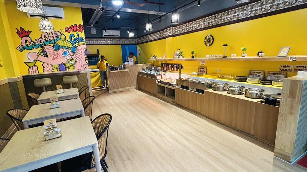 CuriColleの店内。黄色い壁にゾウのイラスト、右側にカレーの鍋やトッピングが並ぶカウンター