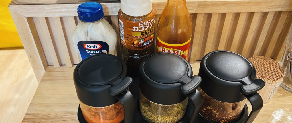 調味料コーナー。タルタルソース、カゴメのとんかつソース、ホットソース、スパイスの容器