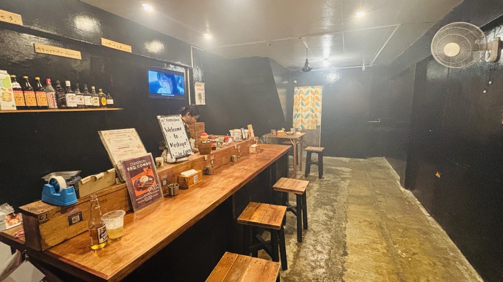 MESHIYAの店内。黒い壁と、奥に向かって長く続く木のカウンター席