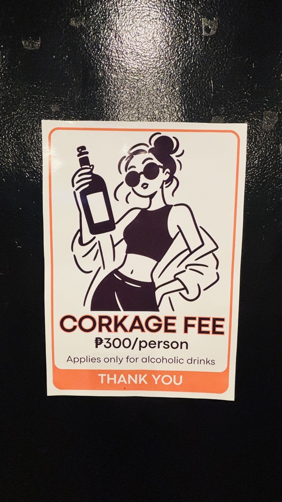 「CORKAGE FEE ₱300/person Applies only for alcoholic drinks」の貼り紙