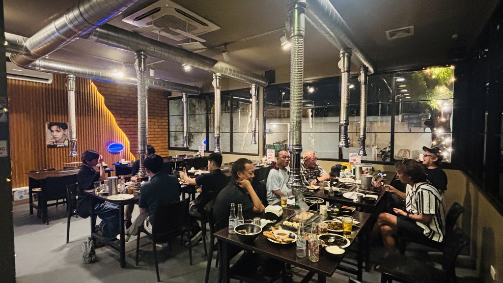 Mr. Lamb Barbequeの店内。テーブルの上に銀色の排気ダクトが並び、壁はレンガと木