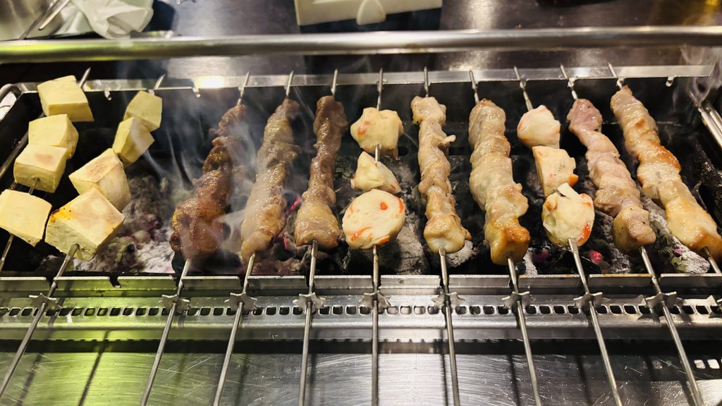炭火の上で回りながら焼ける串。左の黄色い四角はさつまいも