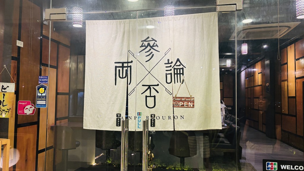参否両論（Sanpiryouron）の入口。店名が大きく書かれた白いのれん
